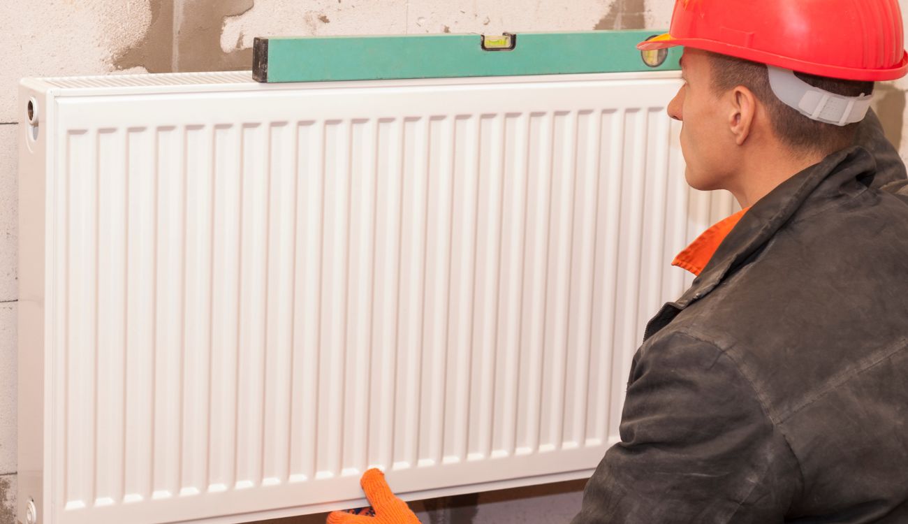 An engineer installing a radiator in a home in the UK