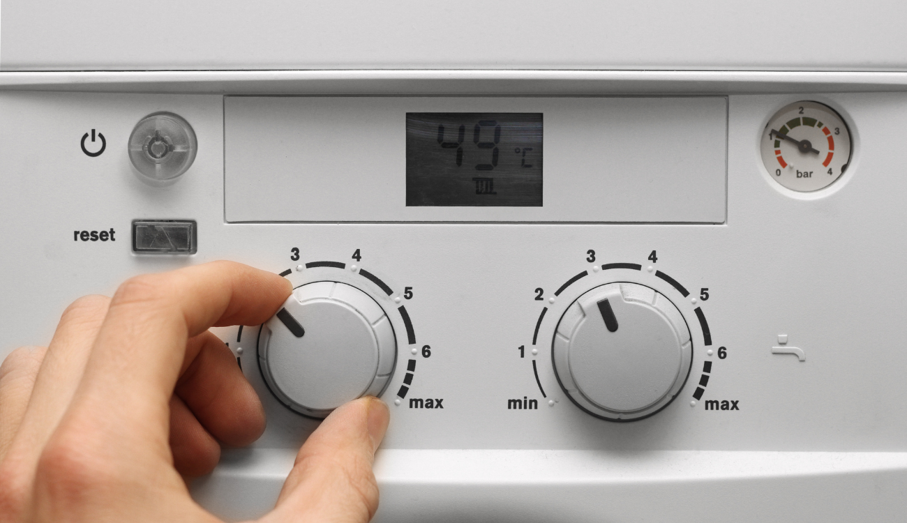 A person adjusting the dials on a combi boiler