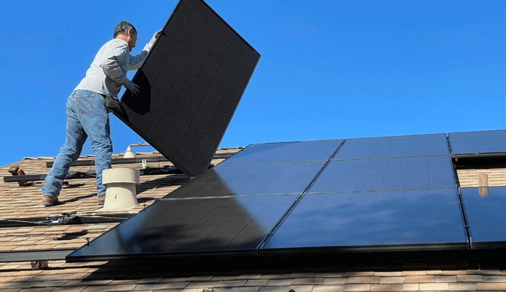 A man installing black solar panels on a roof